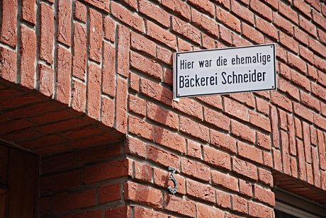 Foto: Schild mit der Aufschrift 'Hier war die ehemalige Bäckerei Schneider'