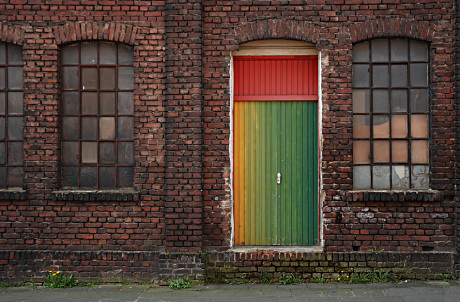 Foto: Farbiges Eingangstor in einer Ziegelfassade