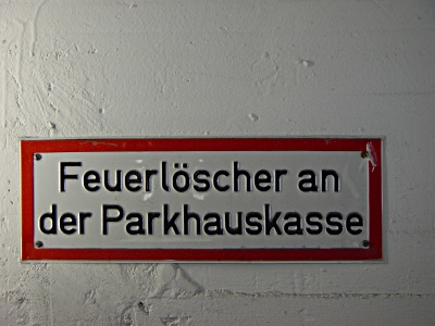 Hinweisschild mit der Aufschrift: Feuerlscher an der Parkhauskasse